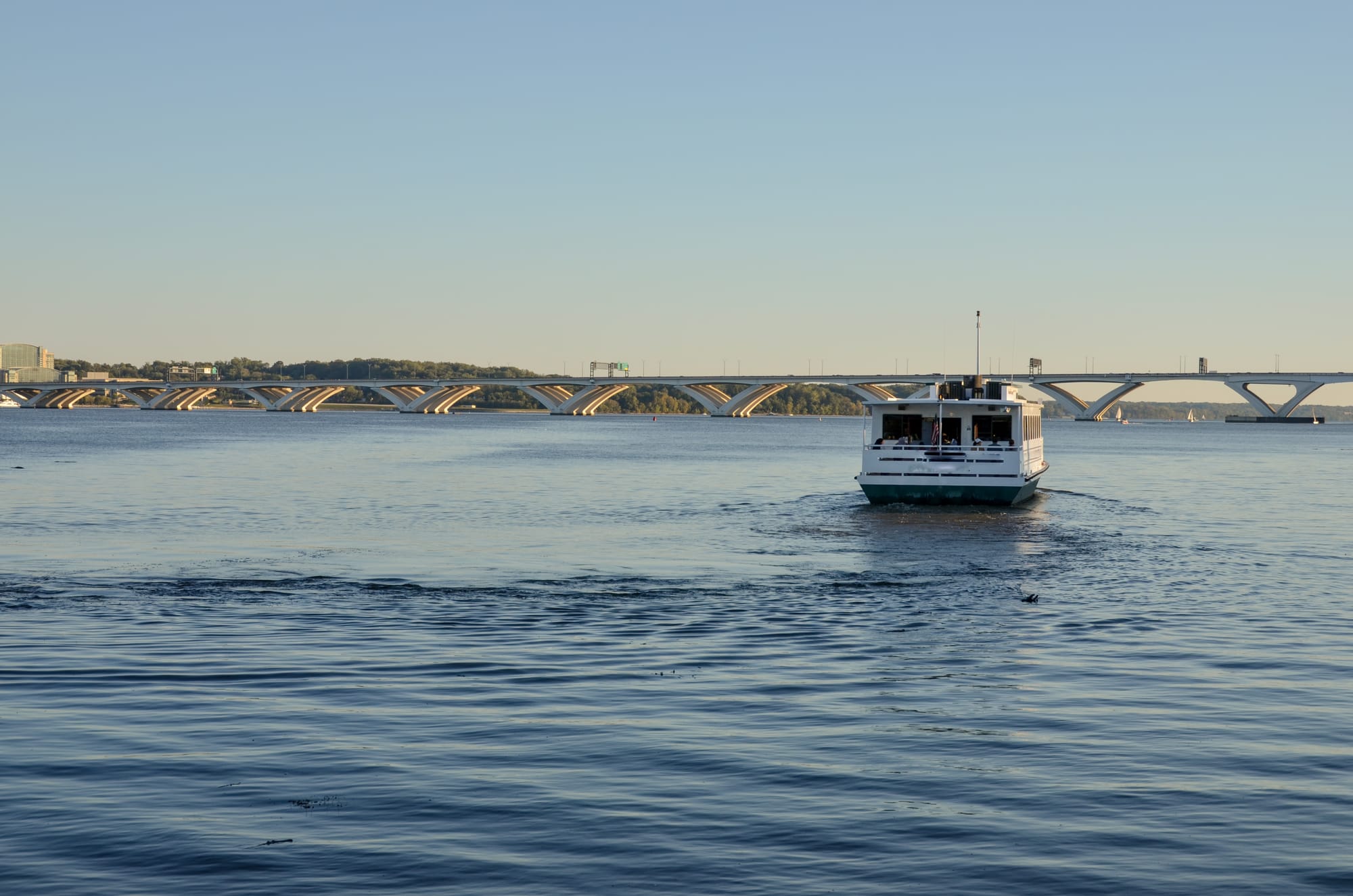 A boat on the Potomac River heading toward a bridge on a calm, clear day.